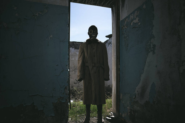 ein Mann mit Gasmaske steht in einem alten Gebäude in der Tür, gut für den Bucheinband - Foto, Bild