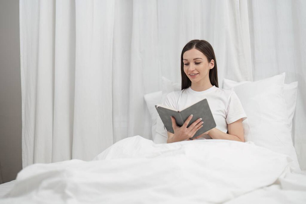 Розслабляюча жінка читає книгу в спальні на свята
. - Фото, зображення