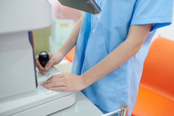 Imagem cortada de enfermeira oftálmica em esfregaços usando equipamentos modernos ao verificar a visão do paciente na clínica - Foto, Imagem