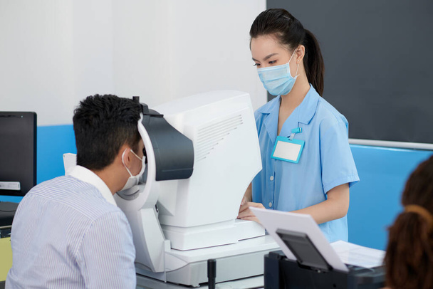 Paziente ottenere gli occhi controllati con rifrattometro per ottenere la prescrizione di occhiali o lenti a contatto - Foto, immagini