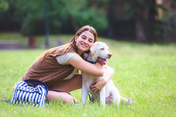 公共公園でかわいいラブラドールレトリバーで遊んで若い女性.犬の親友. - 写真・画像