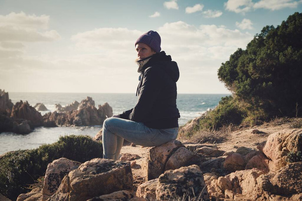 attractive woman dressed in winter clothes sitting by the sea - Foto, immagini