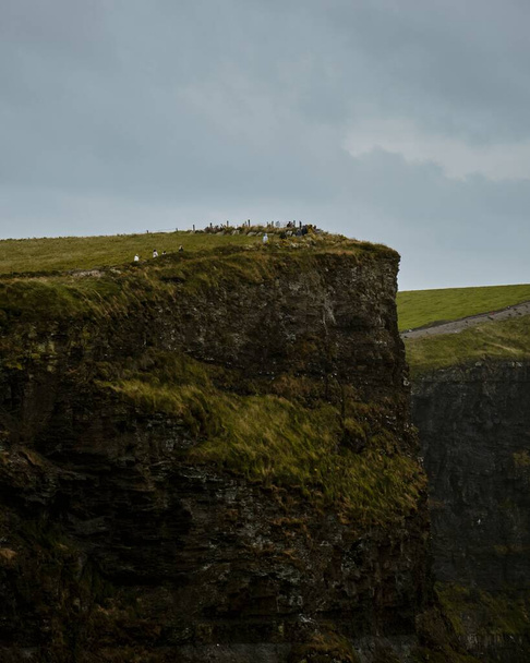 A scenic vertical view of the evergreen Cliffs of Moher in Ireland on a gloomy day - Foto, imagen