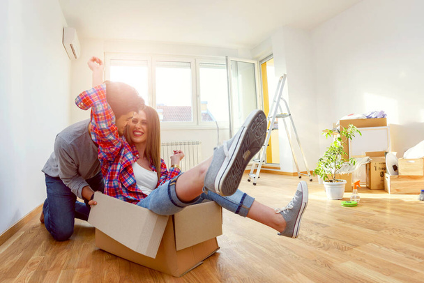 Счастливая молодая пара переезжает в новый дом распаковывать коробки, веселиться
 - Фото, изображение