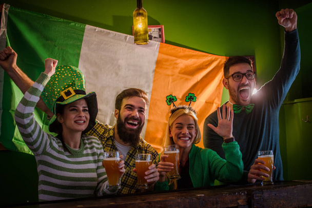 Bir grup arkadaş bira barında Aziz Patrick Günü 'nü kutluyor. - Fotoğraf, Görsel
