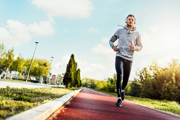 Чоловік біжить вранці на гоночній трасі
 - Фото, зображення
