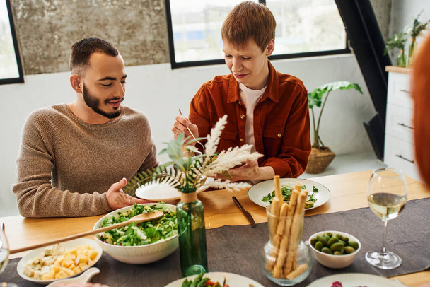 heureux gay homme servir repas près copain près délicieux souper dans moderne cuisine - Photo, image