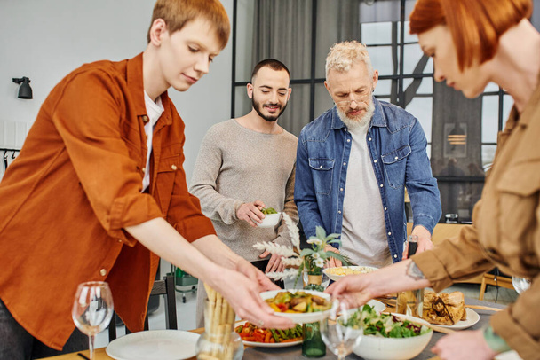 gay hombre setting familia cena cerca padres y novio en cocina - Foto, Imagen
