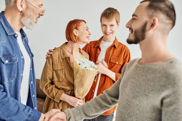 happy gay man looking at boyfriend and father shaking hands on blurred foreground at home - Фото, зображення
