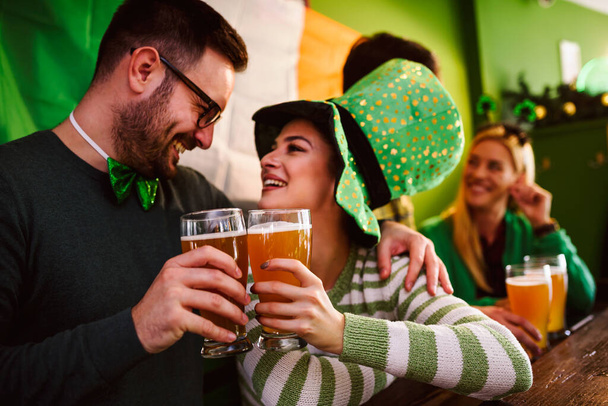 Bir grup arkadaş bira barında Aziz Patrick Günü 'nü kutluyor. - Fotoğraf, Görsel