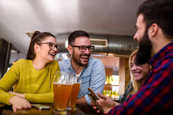 Freunde an der Bar trinken Bier mit Smartphones - Foto, Bild