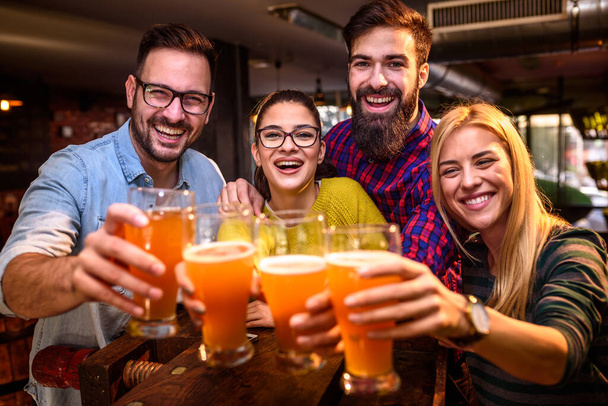 Группа друзей, пьющих пиво в пабе
  - Фото, изображение