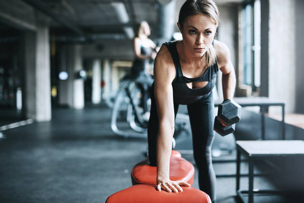 Hingabe macht den Unterschied. eine junge Frau trainiert mit Gewichten in einem Fitnessstudio - Foto, Bild