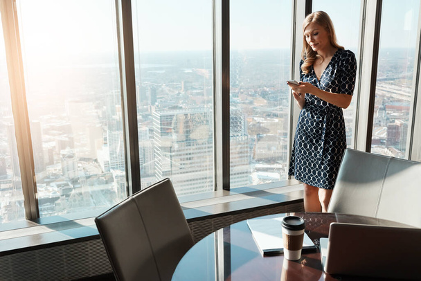 Gestire gli affari direttamente dal suo smartphone. una giovane donna d'affari che usa un cellulare in un ufficio - Foto, immagini