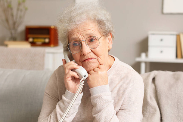 Idősebb nő beszél telefonon otthon, közelkép - Fotó, kép