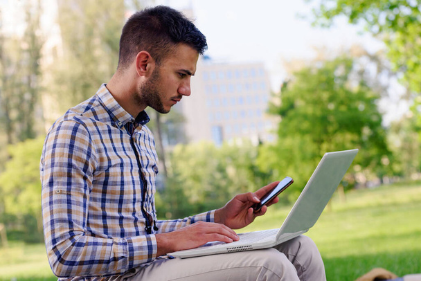 Young businessman with laptop working in the park  - Photo, image