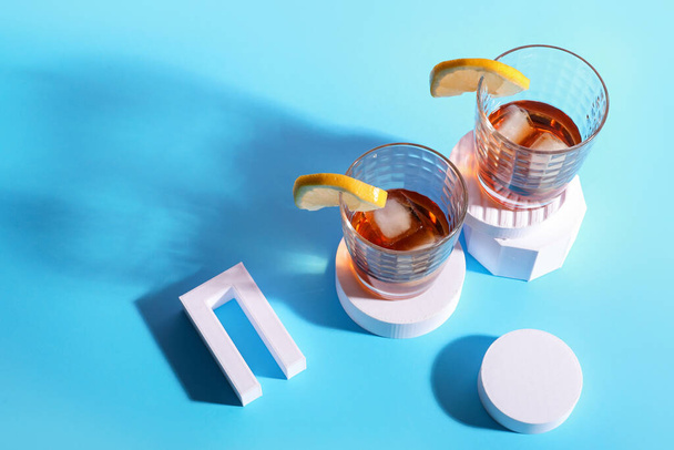 Glasses of rum with ice cubes, lemon slices and plaster figures on blue background - Photo, Image