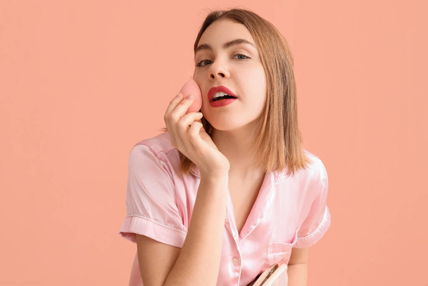 Mladá žena s kosmetickou taškou a make-up houbou na růžovém pozadí, detailní záběr - Fotografie, Obrázek