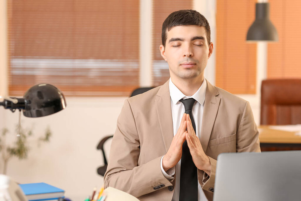 Young businessman meditating in office. Balance concept - Photo, Image