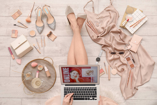 Mulher com laptop, produtos de maquiagem e acessórios de compras on-line no chão de madeira leve - Foto, Imagem