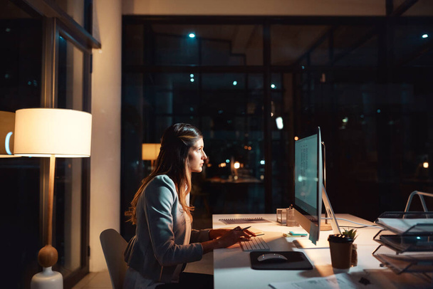Посвящение помогает. молодая бизнесвумен, использующая компьютер поздней ночью на работе - Фото, изображение