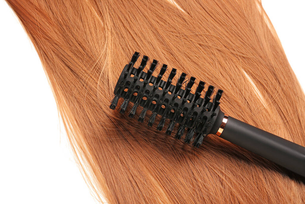 Ginger hair with round brush on white background, closeup - Zdjęcie, obraz