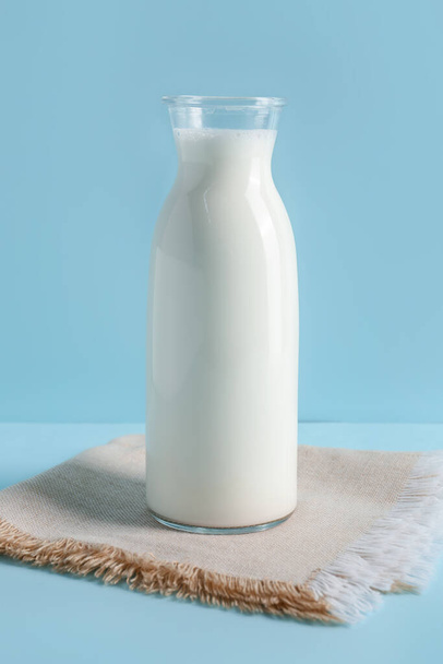 Μπουκάλι με φρέσκο γάλα σε μπλε φόντο - Φωτογραφία, εικόνα