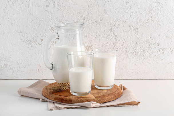 Jarra y vasos con leche fresca sobre fondo blanco - Foto, Imagen