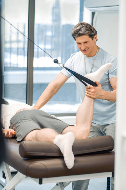 Hyperextension. Male patient having a leg hyperextension in a rehabilitation center - Foto, afbeelding