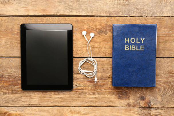 Biblia Święta ze słuchawkami i tabletem na drewnianym tle - Zdjęcie, obraz