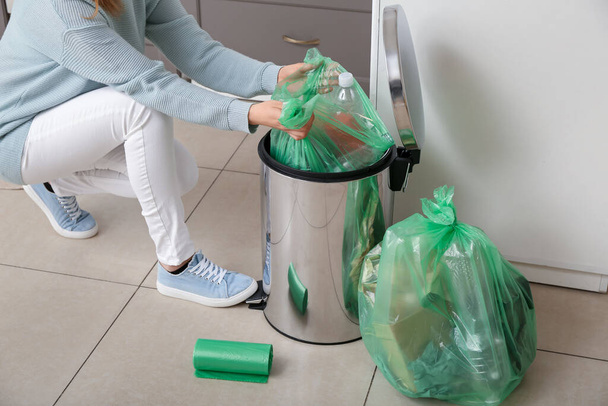 Woman taking full garbage bag from trash bin in kitchen - Foto, Bild