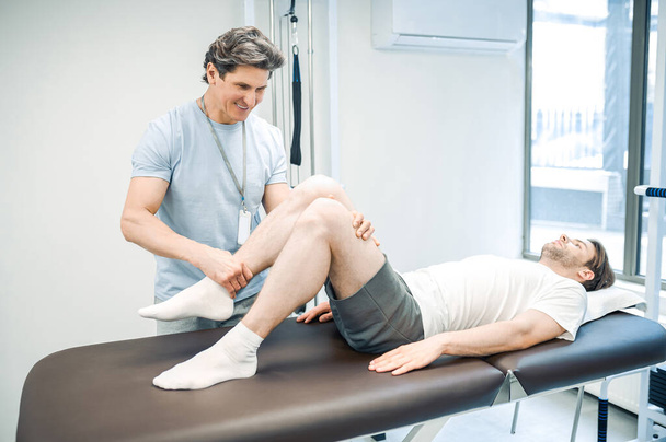 Legs rehabilitation. Male physical therapist working with patients legs - Foto, Imagem