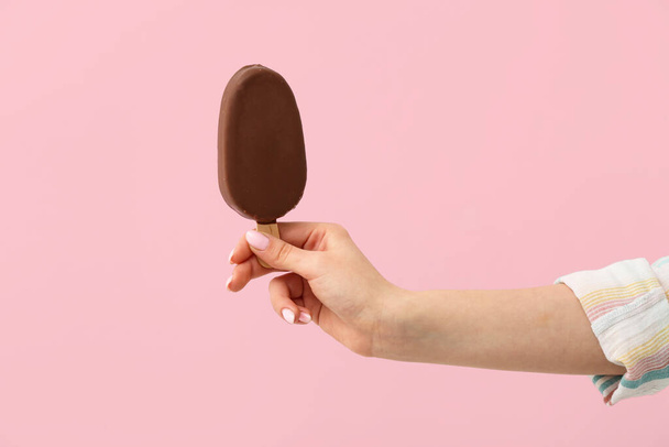 Woman holding delicious chocolate covered ice cream on stick against pink background - Foto, immagini