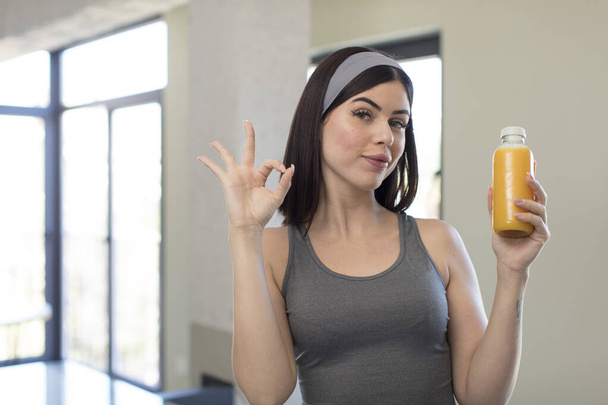 pretty young woman feeling happy, showing approval with okay gesture. orange juice concept - Fotoğraf, Görsel