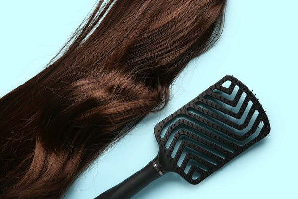 Welliges braunes Haar mit Pinsel auf blauem Hintergrund - Foto, Bild