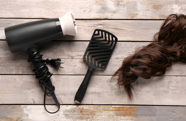 Καστανά μαλλιά με πινέλο και στεγνωτήριο σε ξύλινο φόντο - Φωτογραφία, εικόνα