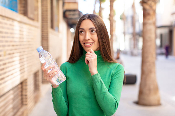 smiling with a happy, confident expression with hand on chin. water bottle concept - Foto, immagini