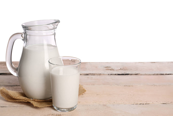 Jarra y vaso de leche sobre la mesa sobre fondo blanco - Foto, imagen
