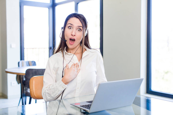 young pretty woman looking shocked and surprised with mouth wide open, pointing to self. telemarketer concept - Photo, Image