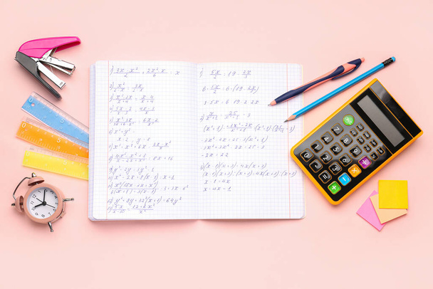 Copybook with maths formulas, calculator, alarm clock and stationery on pink background - Фото, зображення