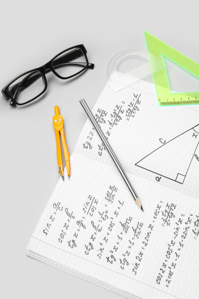 Copybook com fórmulas matemáticas, óculos e artigos de papelaria sobre fundo cinza - Foto, Imagem