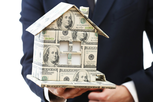 Модель дома из денег в мужской руке изолированы на белом фоне
 - Фото, изображение