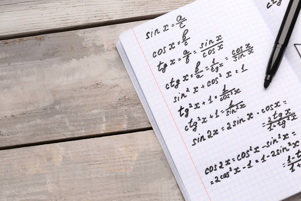 Copybook con formule matematiche e penna su fondo grigio in legno - Foto, immagini