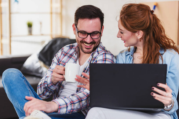 ευτυχισμένο ζευγάρι που χρησιμοποιεί φορητό υπολογιστή στο νέο σπίτι - Φωτογραφία, εικόνα