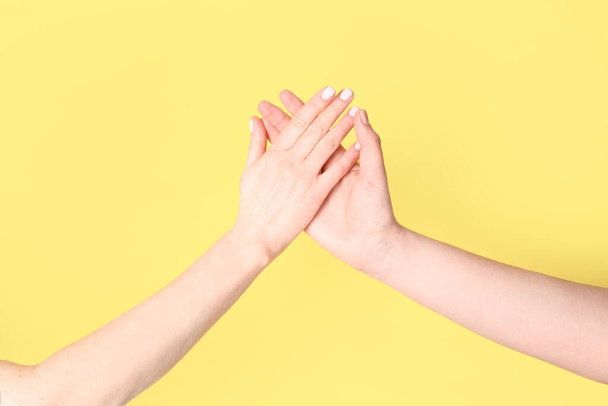 Ženy drží ruce u sebe na žlutém pozadí. Koncept přátelství - Fotografie, Obrázek
