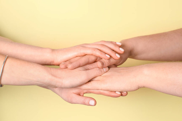 Women putting hands together on yellow background. Friendship concept - Fotografie, Obrázek