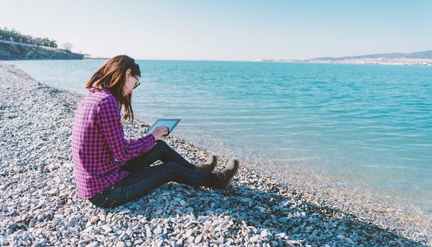 Meisje met tablet op strand - Foto, afbeelding