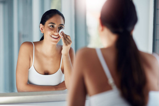 Víz és egy facecloth használata egyszerűen nem elég. egy gyönyörű fiatal nő mossa az arcát pamutgyapjúval a fürdőszoba tükrében. - Fotó, kép