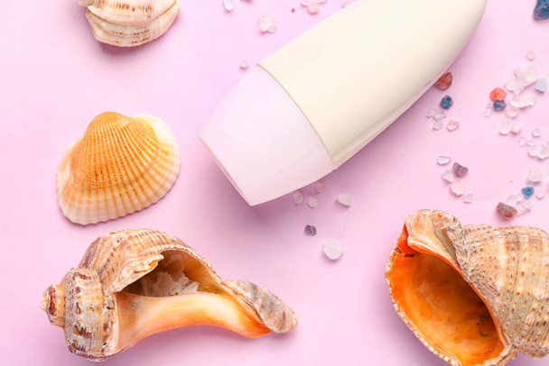 Дезодорант с раковинами и морской солью на розовом фоне - Фото, изображение