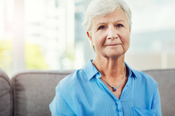 Pensioen heeft lang op zich laten wachten. Gesneden portret van een oudere vrouw zittend op haar bank thuis - Foto, afbeelding